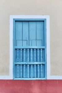 Typical window with blue wooden shutters and bars in the old colonial city of Trinidad, Cuba.